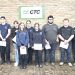 Students and instructors at Greene County CTC pose with certificates in front of a brick wall sign.
