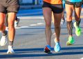 Close-up of runners’ legs and colorful shoes moving along a road during a race.