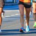 Close-up of runners’ legs and colorful shoes moving along a road during a race.