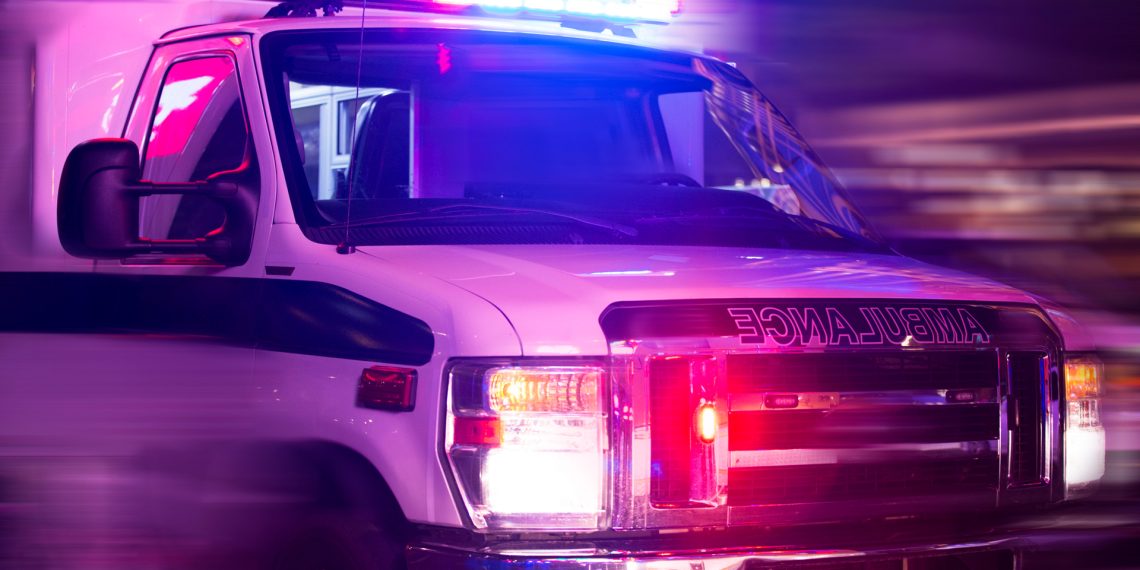 Ambulance with flashing lights driving quickly at night responding to an emergency.