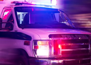 Ambulance with flashing lights driving quickly at night responding to an emergency.