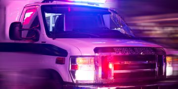 Ambulance with flashing lights driving quickly at night responding to an emergency.