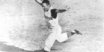 Baseball player in a Pirates uniform runs across the field holding his cap in celebration.
