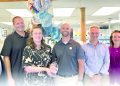 Group of pharmacy staff posing with an award and balloons inside a retail pharmacy.