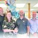 Group of pharmacy staff posing with an award and balloons inside a retail pharmacy.