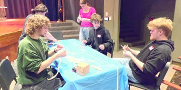 Students build a structure together at a table during a Science Olympiad competition.