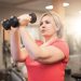 Woman lifting dumbbells during a strength training workout in a gym.