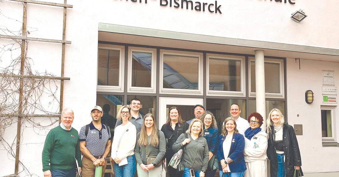 Group of educators posing outside a German school building during an international study trip