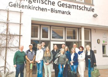 Group of educators posing outside a German school building during an international study trip