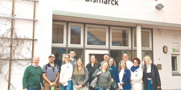 Group of educators posing outside a German school building during an international study trip