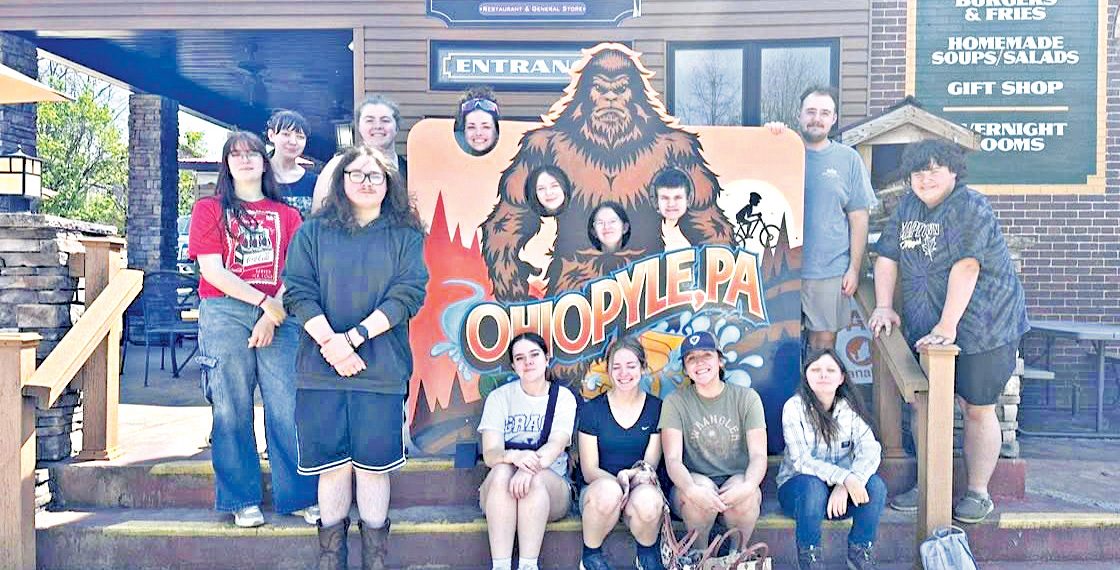 Group of students posing with an Ohiopyle sign outside a market building