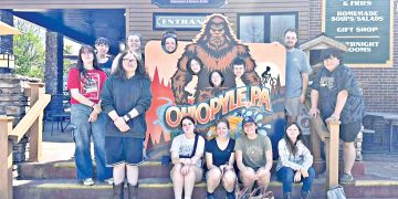 Group of students posing with an Ohiopyle sign outside a market building