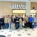 A group of students pose indoors in front of an eHIVE sign holding project displays from a school design activity.