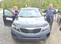 A retired rural mail carrier and mechanic pose beside a Kia Sorento used for mail delivery in Greene County.