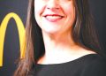 A smiling woman with long dark hair poses for a professional portrait against a black and gold background.
