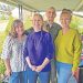 Four family members stand together smiling on a covered porch during a family gathering.