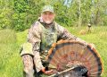 Tammy Hardy posing with turkey in woods.