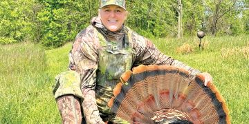 Tammy Hardy posing with turkey in woods.