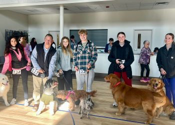 Participants pose with their dogs inside a community center during a community pet walk event.