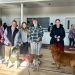 Participants pose with their dogs inside a community center during a community pet walk event.