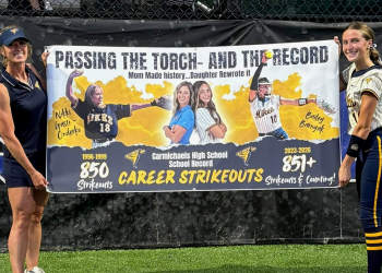 Nikki Gasti Onderko and Bailey Barnyak hold a banner celebrating the Carmichaels High School career strikeout record passing from mother to daughter.