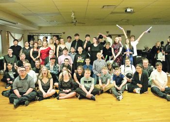 A large group of young participants poses together with balloons and glow sticks during a Black and White Ball celebration.