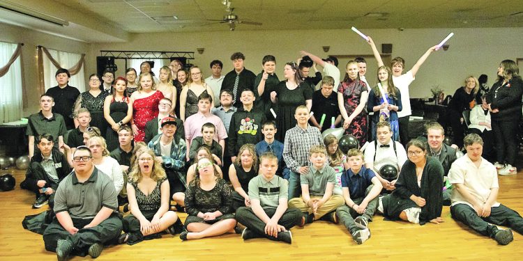 A large group of young participants poses together with balloons and glow sticks during a Black and White Ball celebration.