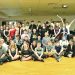 A large group of young participants poses together with balloons and glow sticks during a Black and White Ball celebration.