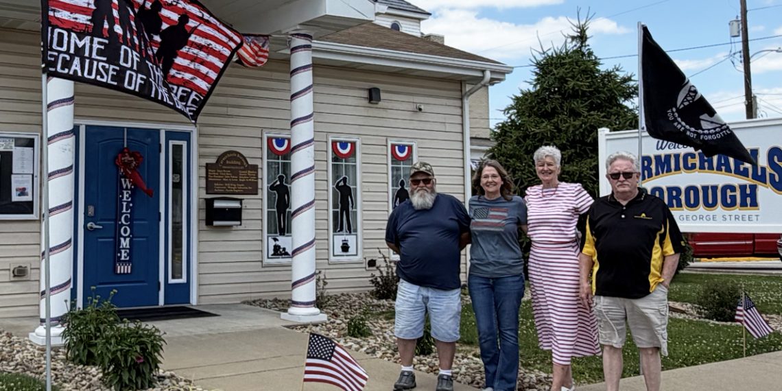 Members of the Carmichaels Borough Council stand outside the decorated borough building during the America 250 celebration in Carmichaels.