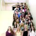 A group of National Honor Society students poses on a staircase inside a school building for a formal group photo.