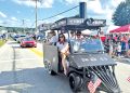 A train themed parade vehicle travels through the Pennsylvania Bituminous King Coal Show parade as spectators watch from the roadside.