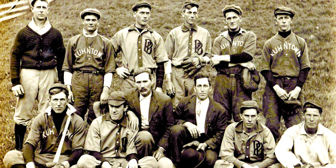 A vintage team photo shows members of the Kuhntown baseball team posing together in uniform on a grassy field.