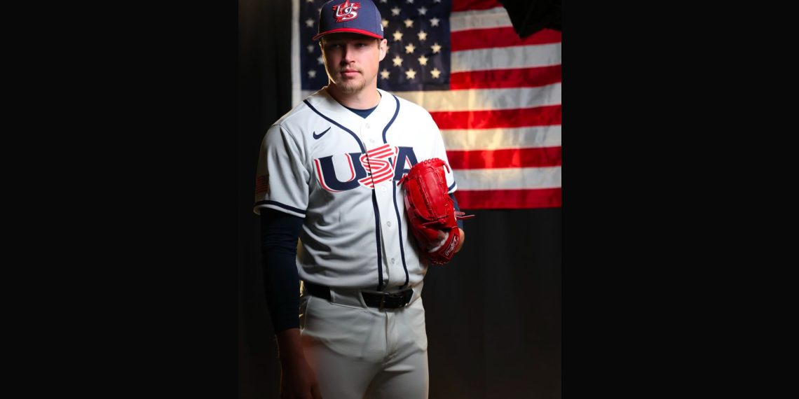 Mason Miller stands in his Team USA baseball uniform holding a red glove in front of an American flag backdrop.