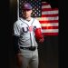 Mason Miller stands in his Team USA baseball uniform holding a red glove in front of an American flag backdrop.