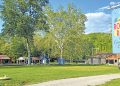 A scenic view of Mon View Park in Greensboro features playgrounds, open grassy areas, large trees, and the Mon View Roller Rink and Community Center sign.