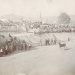 A historic photograph shows spectators watching a harness horse race on a dirt track at an early county fair.