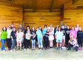 Special Olympics participants, volunteers, and supporters pose together on an outdoor stage during a community picnic.
