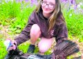 A young hunter poses with a harvested wild turkey in a wooded area during spring turkey season.