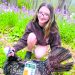 A young hunter poses with a harvested wild turkey in a wooded area during spring turkey season.