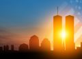A stylized illustration of the Twin Towers rising above the New York City skyline with a faded American flag in the background at sunrise.