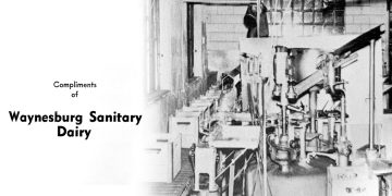 Vintage black and white photo of the Waynesburg Sanitary Dairy processing plant with industrial equipment and the company's name printed on the image.