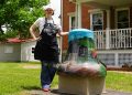 An artist poses beside Greene County's "Coal & Country" painted bell outside the Greene County Historical Society Museum in Waynesburg.