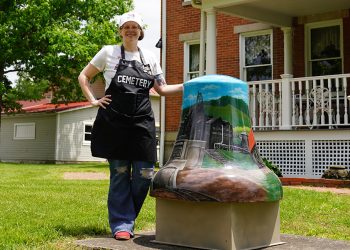 An artist poses beside Greene County's "Coal & Country" painted bell outside the Greene County Historical Society Museum in Waynesburg.