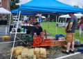 A vintage hay baler demonstration takes place among vendor booths during the Old Glory in Greene County Festival at Bootsie's Bed & Breakfast.