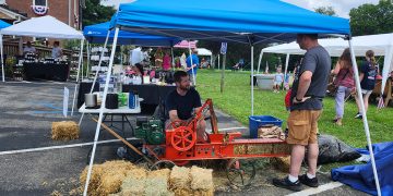 A vintage hay baler demonstration takes place among vendor booths during the Old Glory in Greene County Festival at Bootsie's Bed & Breakfast.