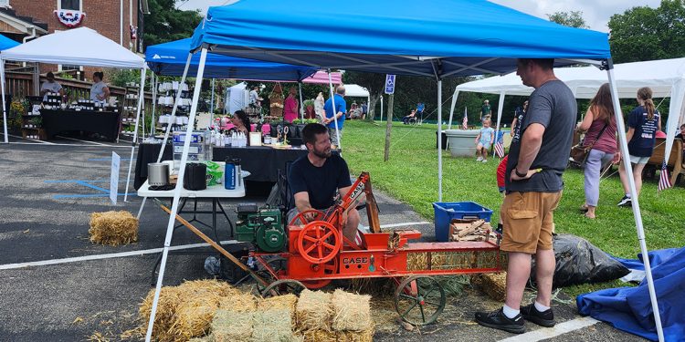 A vintage hay baler demonstration takes place among vendor booths during the Old Glory in Greene County Festival at Bootsie's Bed & Breakfast.