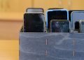 Several smartphones are stored in a wooden classroom organizer used to hold student devices during the school day.