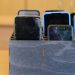 Several smartphones are stored in a wooden classroom organizer used to hold student devices during the school day.