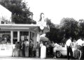 A vintage black and white photo shows customers lined up outside a busy Dari Delite ice cream stand with classic cars parked nearby.