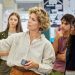 A teacher writes on a whiteboard while several high school students watch during a classroom lesson.